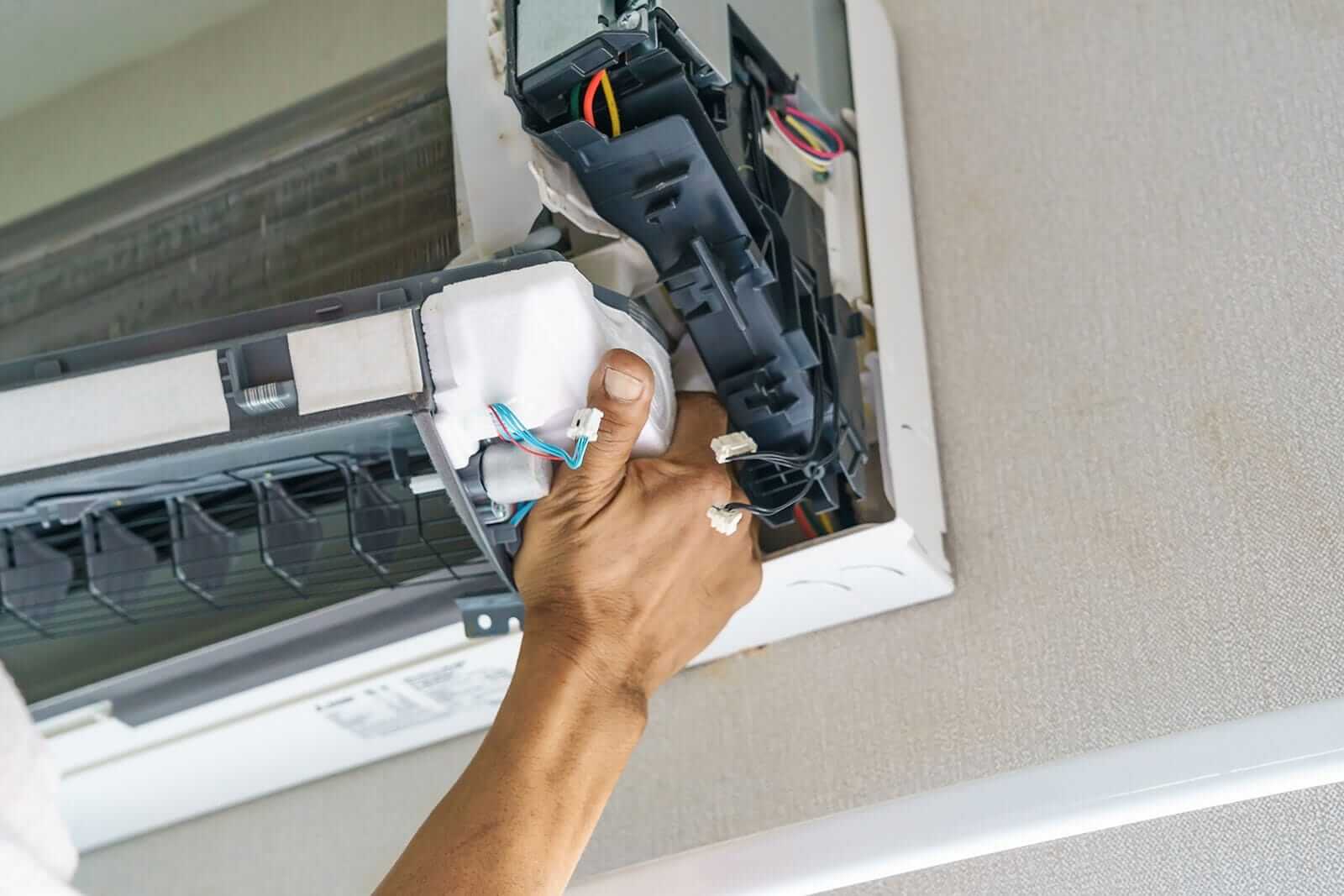 Technician repairing a ceiling air conditioning unit.